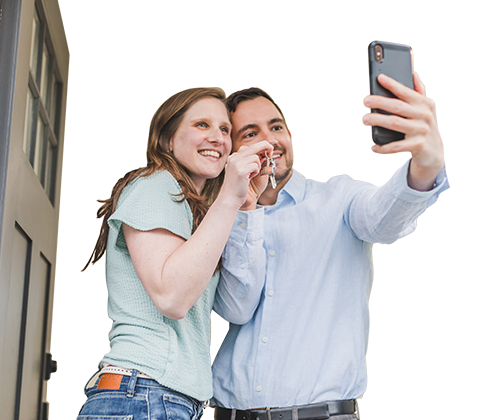 A couple is taking a selfie in front of their door while holding the house key