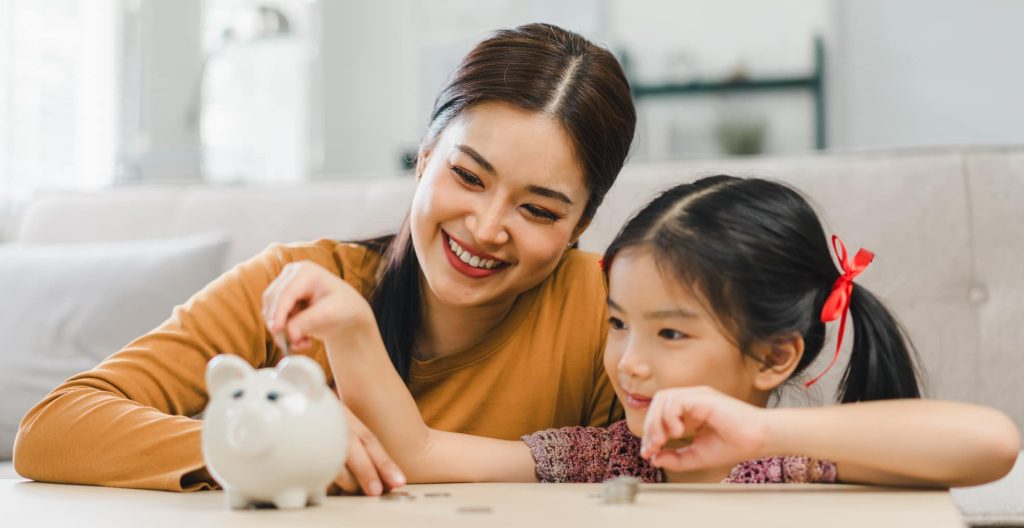 mother and daughter saving money in piggy bank