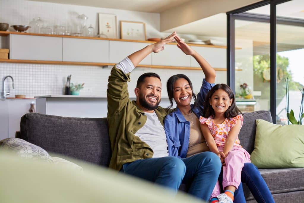 family sitting on couch in new home after mortgage loan